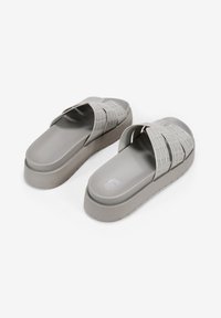 Sandalias moldeadas grises con un diseño de tiras texturizadas en forma de cruz y una suela gruesa con una ligera plataforma. Acabado suave y detalles mínimos.