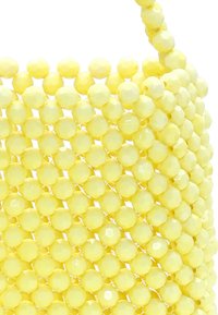 Borsa a tracolla gialla con forma rotonda. Presenta perline esagonali lucide disposte in un motivo intrecciato. Manico elegante con perline simili.
