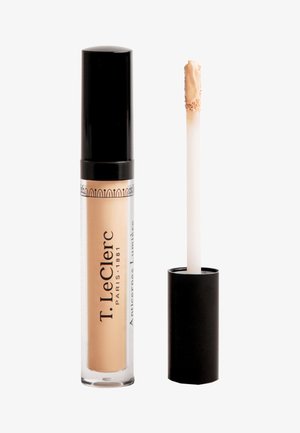 Correttore liquido in un tubetto trasparente con tappo nero, dotato di applicatore a forma di piede di cervo. Il prodotto è di un colore beige chiaro.