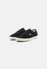 Zwarte suede sneakers met een witte rubberen zool. Kenmerken zijn een low-top ontwerp, ronde neus en contrasterende witte stiksels langs de naden.