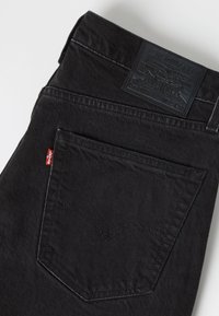 Περιοχή πίσω τσέπης μαύρων τζιν Levi's με κόκκινη ετικέτα Levi's και μαύρο δερμάτινο λογότυπο στη μέση.