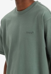 Zelené tričko z bavlny s krátkými rukávy a kulatým výstřihem. Logo Levi's je subtilně embosováno na hrudi. Hladká textura.