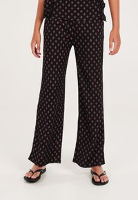 Zwarte wijde broek met een patroon van kleine diamanten in het roze. Gemaakt van zachte stof, hebben ze een ontspannen pasvorm.