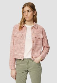Roze geweven jasje met twee borstzakken, bruine knopen en lange mouwen. Draag het over een gestreept shirt en olijfgroene broek.