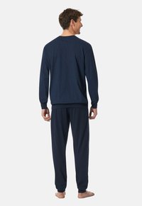 Conjunto de ropa de estar por casa en azul marino que incluye una blusa de manga larga con un patrón de cuadros y pantalones a juego. Tela suave y ajuste relajado.