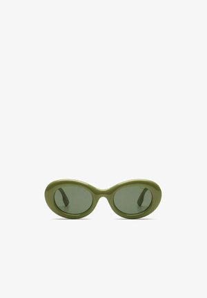 Lunettes de soleil vert olive avec des verres ovales, une monture épaisse en plastique et des branches courbées. Les verres sont teintés d'un vert foncé, offrant un contraste.
