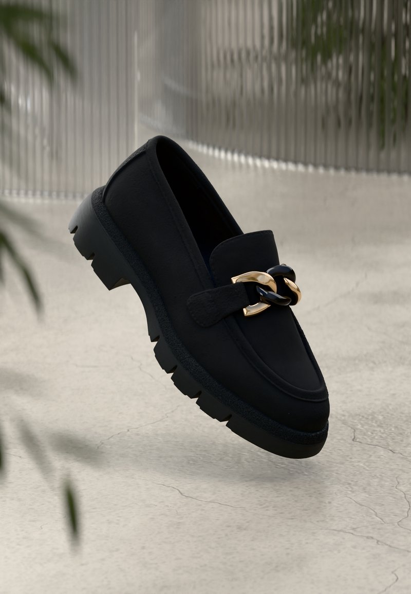 Mocassins noirs en cuir avec un détail chaîne dorée brillante. Semelle en caoutchouc épaisse avec bords texturés, surface supérieure lisse et design classique.