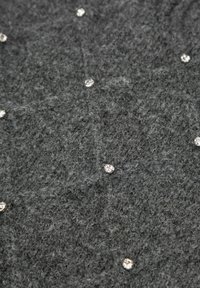 Szara dzianina o miękkiej fakturze zdobiona jest rozproszonymi, przezroczystymi aplikacjami z kryształowych cyrkonii na całej powierzchni.