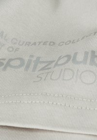 Light gray fabric with a smooth texture featuring printed text in a darker gray. Includes visible stitching along the edge.