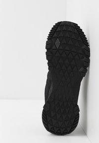 Semelle de chaussure de sport noire avec une surface en caoutchouc texturée présentant un motif de bande de roulement en diamant et des accents latéraux pour l'adhérence et la durabilité.
