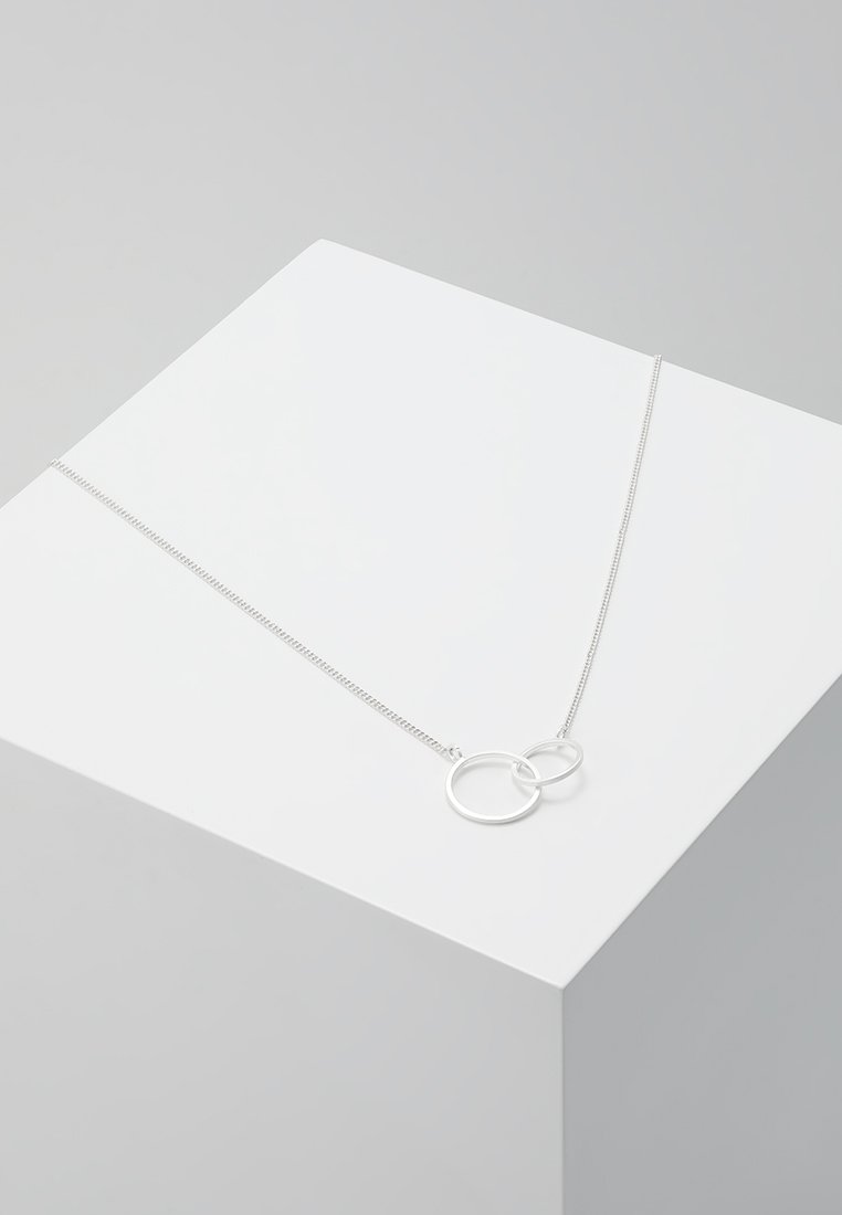 Silberne Halskette mit zwei miteinander verbundenen Kreisen an einer feinen Kette, die ein elegantes, poliertes Metallfinish und ein minimalistisches Design zeigt.
