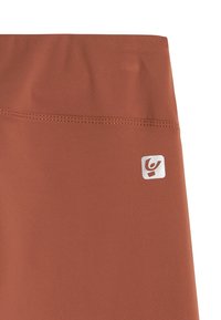 Leggings terracota con textura suave, cintura alta y un pequeño detalle de logotipo blanco en el lado izquierdo.