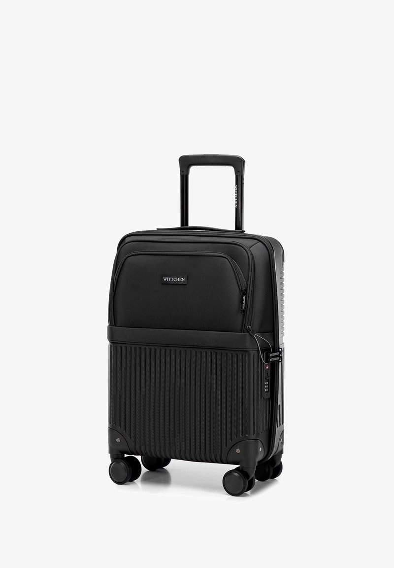 Kompaktowa czarna walizka na kółkach z teleskopową rączką, przednią kieszenią na suwak, żebrowaną twardą dolną częścią oraz wbudowanym zamkiem TSA po prawej stronie.