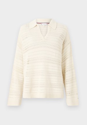 Sweater de malha creme com gola em V, apresentando um padrão texturizado com riscas alternadas abertas e sólidas. Mangas longas, barra canelada.