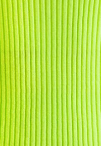 Ein strukturiertest Stoff in leuchtendem Limettengrün mit vertikalen Rippmustern, der ein weiches, gestricktes Aussehen präsentiert.