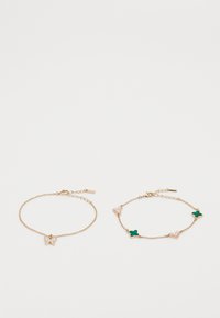Pulsera de cadena en tono dorado que presenta un charm de mariposa, junto con otra pulsera adornada con formas de corazón y trébol de cuatro hojas en tonos rosa y verde.