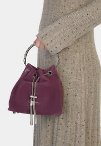 Borsa secchiello bordeaux in camoscio con manico rotondo, coulisse e dettagli in metallo, caratterizzata da nappine e fondo strutturato.