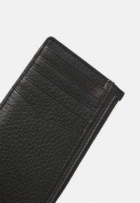 Black leather wallet with textured finish, featuring multiple card slots and a zippered compartment along the edge.