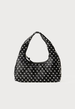Schwarze Handtasche mit kurzem Henkel, bedeckt mit gleichmäßig verteilten silbernen Nieten, vor einem schlichten weißen Hintergrund.
