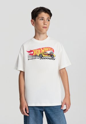 Maglietta bianca in cotone con un colorato grafico "Hot Wheels" che presenta una macchina da corsa gialla, fiamme rosse e strisce nere.