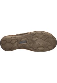 Suela de zapato con un diseño de goma marrón texturizada, que presenta un patrón hexagonal para mayor agarre y un parche negro con el logo cerca del talón.