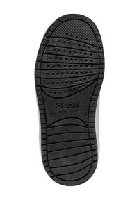 Semelle en caoutchouc noir avec des motifs texturés, des trous de drainage et un logo bien visible. Bords lisses, design courbé et motifs de traction robustes.