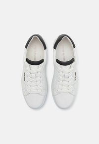 White leather sneakers with a black heel cap, round toe, and lace-up design. Interior features brand name in light lettering.