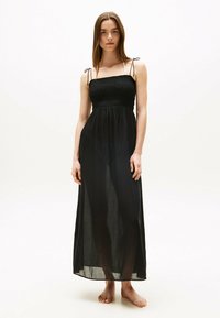 Zwarte maxi-jurk met een gerimpeld lijfje, dunne verstelbare bandjes en doorschijnende stof, wat zorgt voor een vloeiend silhouet. Vloerlange uitvoering.