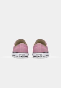 Pink canvas sneakers with a low-top design, white rubber soles, black accents, and contrasted stitching. Brand logo on the heel.