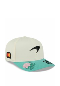 Weißer Baseballcap mit türkisfarbenem Schirm, versehen mit dem schwarzen Nike-Logo, einem Mastercard-Patch und einem gestickten rosa Blumenmotiv.