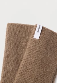 Guantes marrones de punto con un acabado texturizado, con una etiqueta blanca cosida en un lado que muestra "SAMSOE".