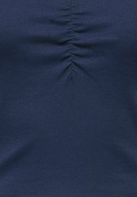 Υφασμα σε ναυτικό μπλε με ριμπ ύφανση και κεντρική κάθετη ραφή με ρυτιδώσεις, δημιουργώντας συγκεντρωμένη υφή.