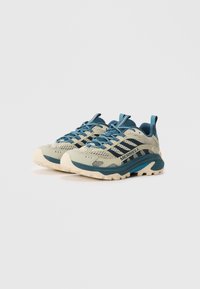 Buty trekkingowe Merrell w jasnej zieleni i teal, z siateczkową cholewką, wzmocnionym noskiem oraz wytrzymałą białą podeszwą zapewniającą przyczepność.