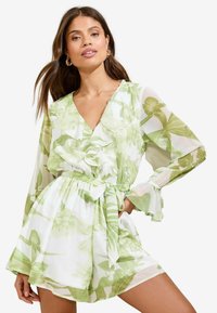 Zaļš ziedu raksts rompers, izgatavots no viegla auduma, ar V veida kakla izgriezumu, volānu detaļām, garām caurspīdīgām piedurknēm un saistāmu jostu.