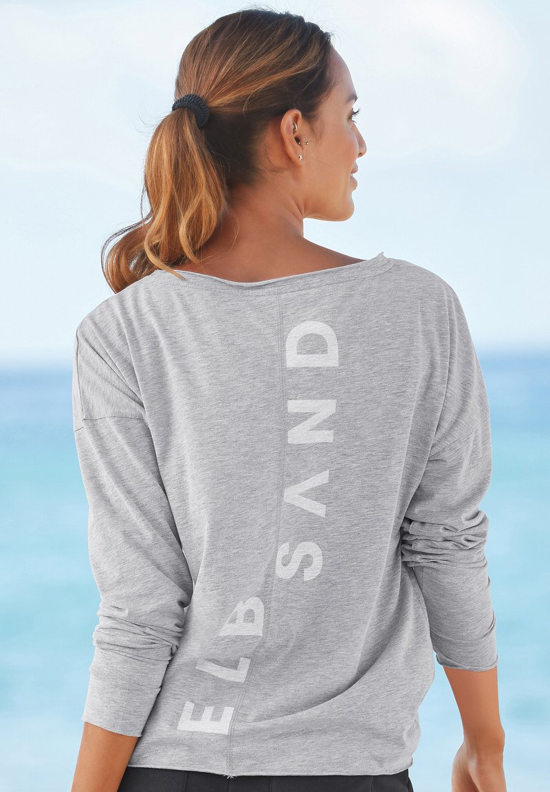 Graues Langarmshirt mit lockerer Passform, das den Schriftzug "ELB SAND" auf der Rückseite trägt. Weicher Stoff mit glatter Textur, ideal für die Freizeit.