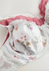 Flersfarvet bh med blomsterprint på hvidt stof, med blonder i lyserød og hvid, samt en blød netunderlag.