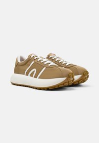 Sneaker sportive marroni con dettagli bianchi, punta tonda, design con lacci e suole in gomma testurizzata con motivi di trazione circolari.