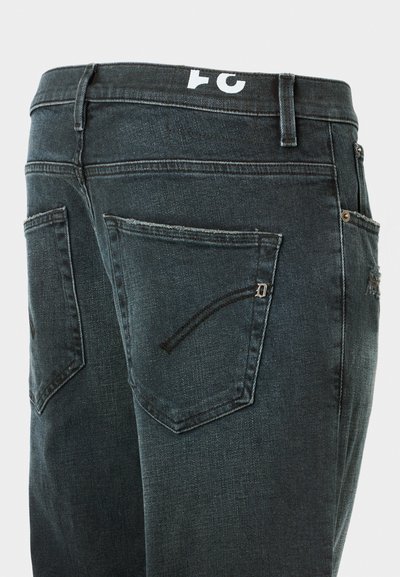 Jeans de mezclilla oscura con corte ajustado, que presentan dos bolsillos traseros y un pequeño detalle de cremallera en el bolsillo izquierdo. Logo blanco en la cinturilla.