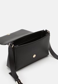 Svart läder crossbody-väska med en pebble-textur, med en magnetisk klaffspänne, justerbar rem och detaljer i guldton.