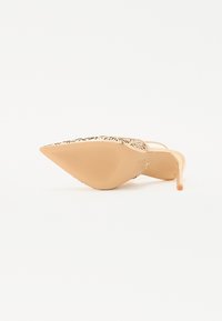 Beige høyhælte sko med spiss tå og mønstret overdel. Elegante stiletthæler og teksturert såle med riller.