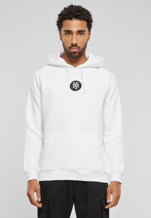 Weißer Kapuzenpulli mit Kängurutasche, verstellbarem Kordelzug an der Kapuze und einem runden schwarzen Logo auf der Brust. Hergestellt aus weichem, strukturiertem Stoff.