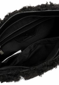 Interno della borsa con texture in pelliccia nera, foderato in morbido tessuto nero, con più scomparti tra cui una tasca con cerniera.