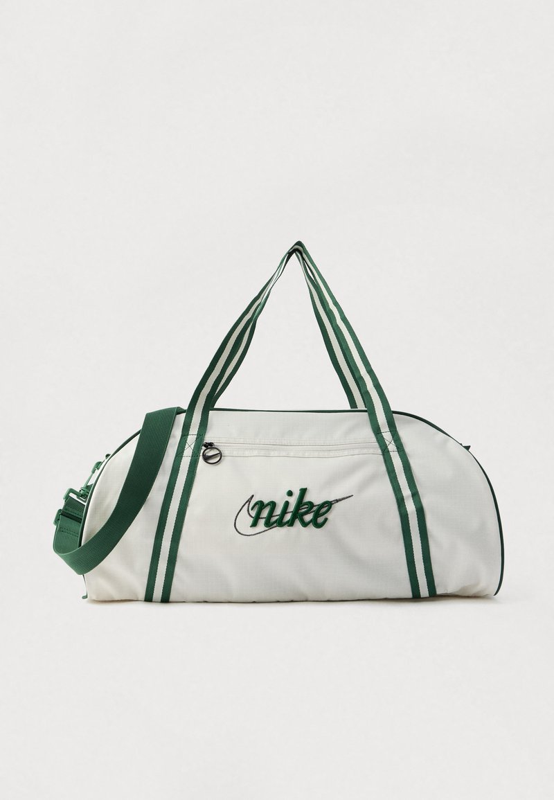 Λευκή τσάντα duffel με πράσινες ρίγες και κεντήματα. Διαθέτει δύο λαβές, ρυθμιζόμενο ιμάντα ώμου και κλείσιμο με φερμουάρ.