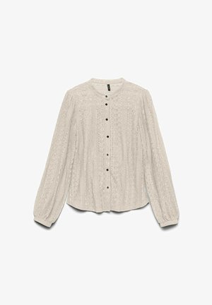 Svetlo bež bluza z dolgimi rokavi, okroglim ovratnikom in zapiranjem na gumb. Teksture tkanine vsebujejo cvetlične vzorce in črne gumbe.