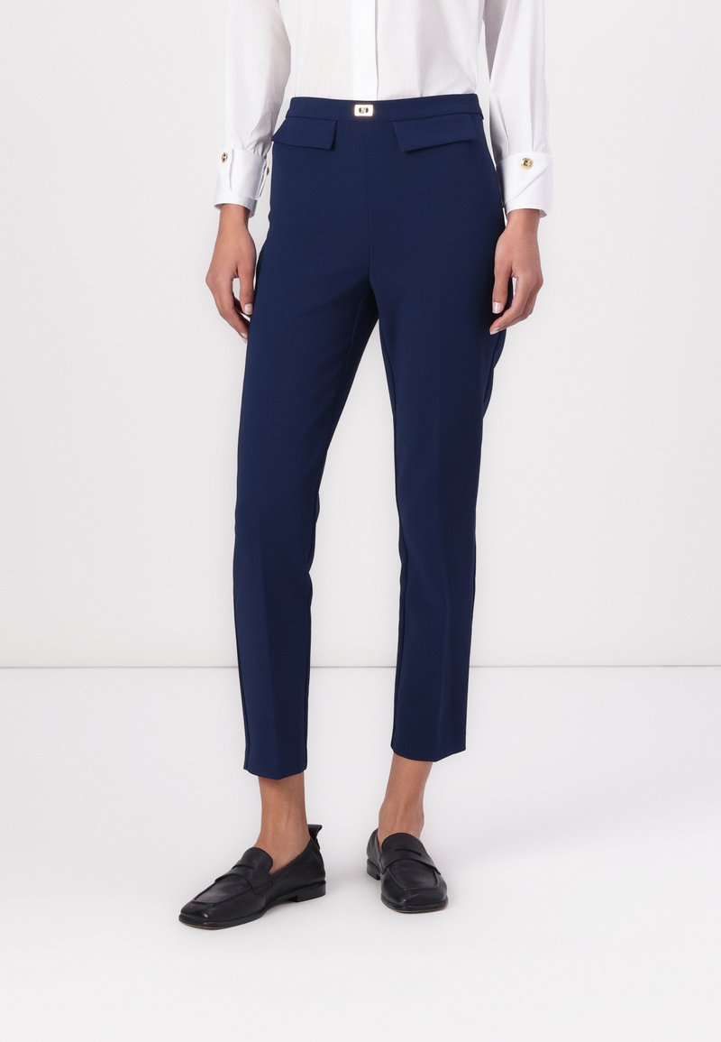 Ναυτικό μπλε κομμένα παντελόνια από μαλακό, ελαστικό ύφασμα. Διαθέτουν στενή εφαρμογή, δύο μπροστινές τσέπες και μέση με χρυσά κουμπιά.