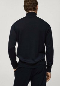 Dunkelblauer Pullover aus weichem Stoff mit hohem Kragen, langen Ärmeln und einer taillierten Taille. Saubere, glatte Textur mit minimalen Details.