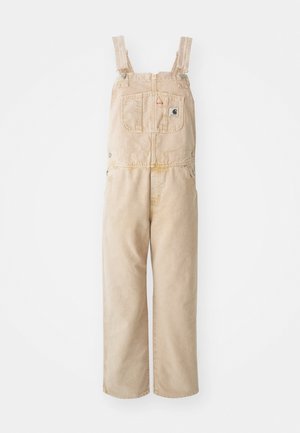 Beige overall gemaakt van stevig materiaal, met verstelbare banden, een voorkantzak en wijde pijpen met een licht vervaagd patroon.