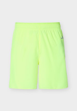 Neonowo żółto-zielone sportowe szorty z elastycznym paskiem w talii i małym szarym logo na prawej udzie, przedstawione na białym tle.