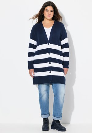 Navy- und weiße gestreifte Strickjacke mit V-Ausschnitt, gerippter Textur, langen Ärmeln und Knöpfen vorne, getragen über hellblauen, umgeschlagenen Jeans.