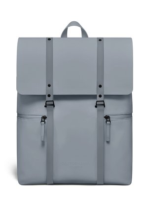 Lys grå ryggsekk med toppklaff, to vertikale stropper med spenner, to glidelåslommer på sidene og et bærehåndtak på toppen.